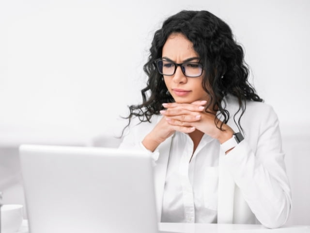 Mulher séria olhando confusa para o laptop