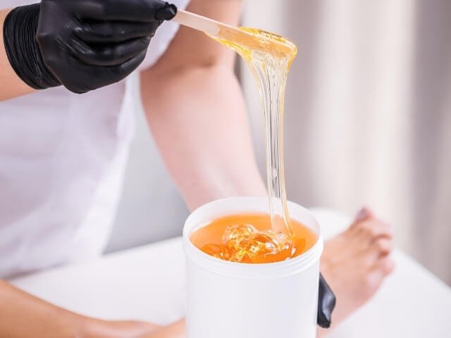 Profissional preparando cera, para fazer cursos de depilação online
